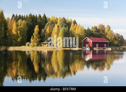 Boathouse et rouge un petit sauna à l'autre côté de la rivière , Finlande Banque D'Images
