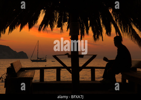 La Grèce. Zakynthos. Zante. Île grecque. Octobre. L'homme regardant le lever du soleil à Keri baie à l'île de Marathonisi. Banque D'Images