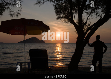 Grèce. Zakynthos. Zante. Île grecque. Octobre. Homme observant le lever du soleil sur la mer baie de Keri regardant vers l'île de Marathonisi. Tamaris. Banque D'Images