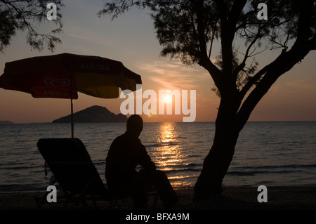 Grèce. Zakynthos. Zante. Île grecque. Octobre. Homme observant le lever du soleil sur la mer baie de Keri regardant vers l'île de Marathonisi. Tamaris. Banque D'Images