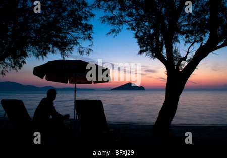 Grèce. Zakynthos. Zante.October. Homme en vacances regardant le lever du soleil sur la mer à Keri Bay regardant l'île de Marathonisi. Tamaris. Banque D'Images