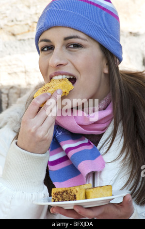 Jeune femme avec chapeau en laine eating cake Banque D'Images