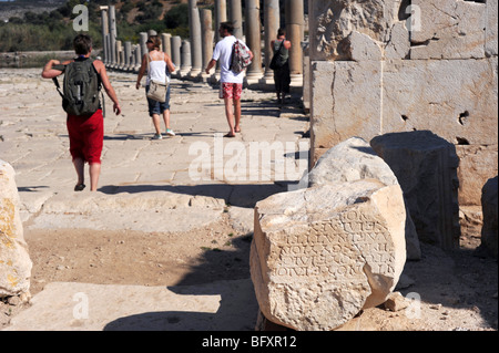 Les touristes à pied par colonnes anciennes qui bordent la voie dans les ruines de Patara Banque D'Images