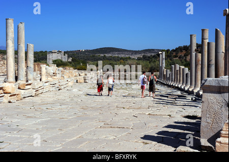 Les touristes à pied par colonnes anciennes qui bordent la voie dans les ruines de Patara Banque D'Images