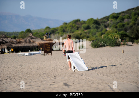 Un touriste fait glisser une chaise longue dans le sable sur la plage de Patara Banque D'Images