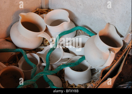 Cruches de lait en pot non émaillées et un morceau de corde verte dans un coffre à thé abandonné dans un studio de potiers Banque D'Images