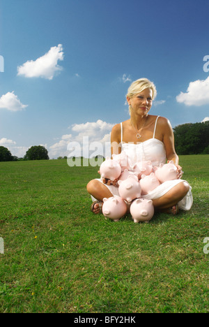 Femme assise avec Piggy Banks Banque D'Images