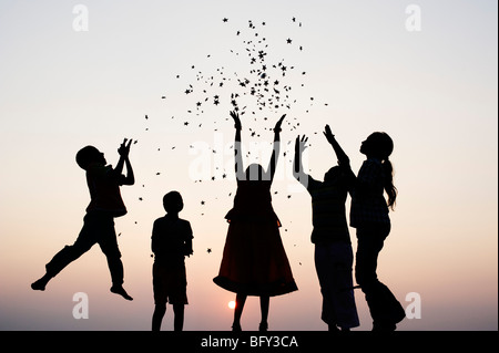 Silhouette de jeunes enfants indiens du saut et du lancer étoiles au coucher du soleil. L'Inde Banque D'Images