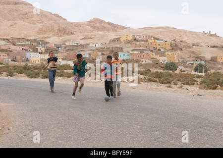 Les garçons jouent au football soccer sur route à Cisjordanie près de Gournah vieux village désert Egypte Louxor. Banque D'Images