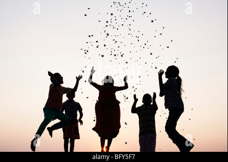 Silhouette de jeunes enfants indiens du saut et du lancer étoiles au coucher du soleil. L'Inde Banque D'Images