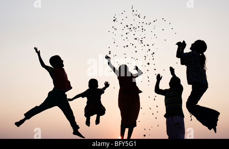 Silhouette de jeunes enfants indiens du saut et du lancer étoiles au coucher du soleil. L'Inde Banque D'Images