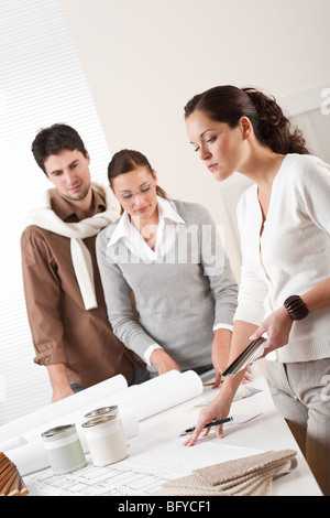 Jeune femme d'intérieur réussie avec deux clients à choisir des couleurs de bureau Banque D'Images