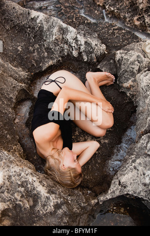 Femme couchée sur des pierres sur la plage Banque D'Images