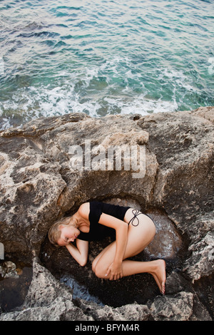 Femme couchée sur des pierres sur la plage Banque D'Images