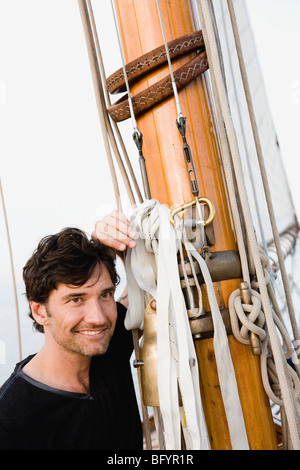 Homme assis sur le pont du bateau à voile Banque D'Images