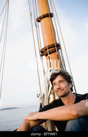 Homme assis sur le pont du bateau à voile Banque D'Images