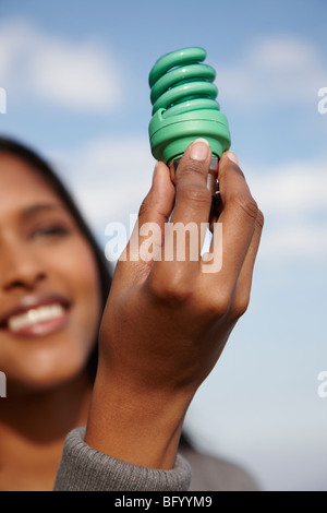 Woman holding up green light bulb Banque D'Images