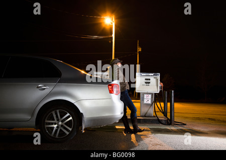 Woman refueling car at night Banque D'Images