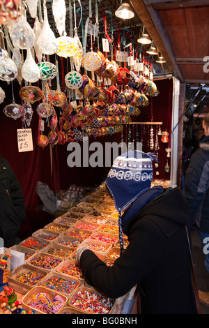 Royaume-uni, Angleterre, Manchester, Albert Square, petit marché de Noël jeune shopper à verre fait main tree decorations stall Banque D'Images