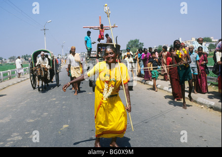 Une robe jaune dévot est venu d'un village lointain et danses en transe son chemin à travers les rues de Palani, l'Inde pour atteindre le Temple d'Periyanayaki au cours de l'assemblée annuelle Thaipusam festival. Elle est menée avec des cordes qui ont été attrapés dans son dos par un autre pèlerin. C'est considéré comme un acte de dévotion. La mortification de la chair en perçant la peau, de la langue ou les joues avec brochettes est également commune. Un homme attaché à une croix de fortune sur un véhicule agricole, l'émulation de la crucifixion du Christ expose son propre acte de dévotion. Banque D'Images