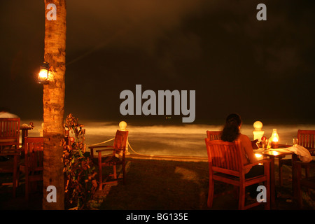 Une femme assise à l'extérieur et bénéficie d'une lampe allumée repas au Galle Face Hotel de Colombo, Sri Lanka. Banque D'Images