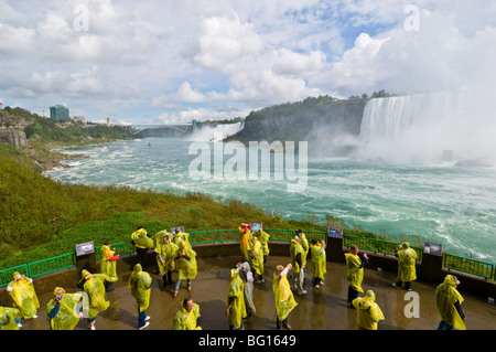 Les touristes en jaune d'imperméables, les chutes canadiennes tout en cascade sur l'Excursion sous les chutes d'', Niagara Falls, Ontario, Canada Banque D'Images