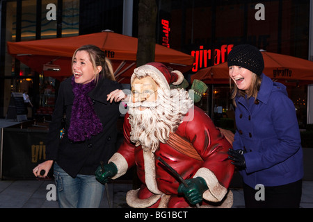 Royaume-uni, Angleterre, Manchester, Spinningfields, deux filles de rire autour de la figure du Père Noël Banque D'Images