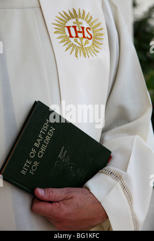 Un prêtre catholique s'apprête à baptiser un enfant. Banque D'Images