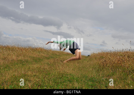 Jeune femme blanche faisant la roue et sauter sur la dune les bras asymétrique déséquilibré Banque D'Images