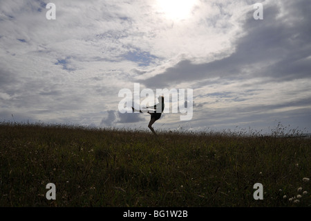 Jeune femme blanche sauter et sauter sur la dune les jambes dans l'air déséquilibré déséquilibrée Banque D'Images
