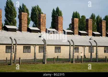 Clôture électrique de périmètre à Auschwitz camp de la mort nazi, avec bloc cuisine restauration et cheminées derrière. Oswiecim, Pologne. Banque D'Images