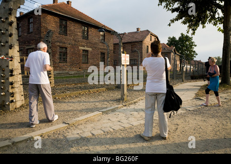 Les touristes voir périmètre clôture électrique à Auschwitz camp de la mort nazi. Oswiecim, Pologne. Hébergement pour les blocs sont derrière Banque D'Images