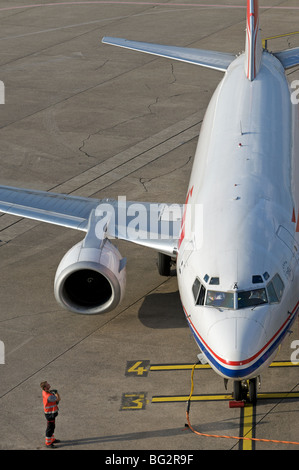 Le personnel au sol à l'aide d'un signal de la main pour communiquer avec un pilote d'un avion de passagers Boeing 737 Banque D'Images