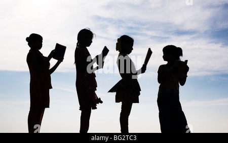 Silhouette d'Indian girls reading books debout dans une ligne Banque D'Images