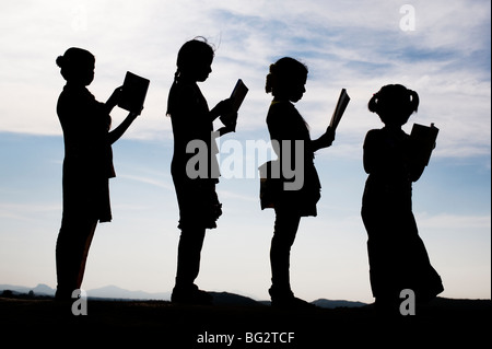 Silhouette d'Indian girls reading books debout dans une ligne Banque D'Images