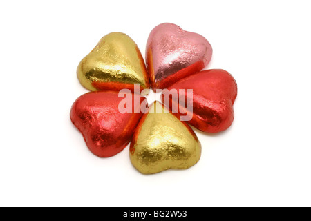 Chocolats en forme de coeur disposés en modèle floral sur fond blanc Banque D'Images