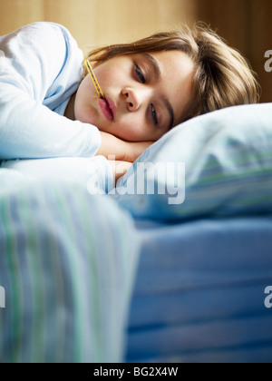 Girl holding thermomètre dans bed Banque D'Images