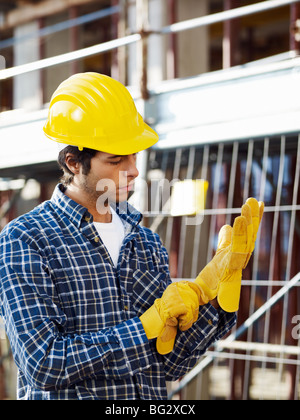 Construction Worker putting on Protective Gloves Banque D'Images