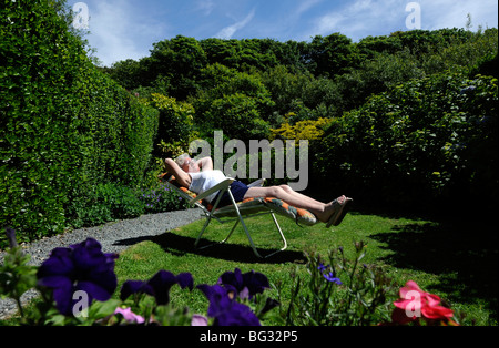 Vieille dame de l'ÂGE DE LA RETRAITE AU SOLEIL PENSIONNÉ BÉNÉFICIE D'UN JARDIN BRITANNIQUE UK Banque D'Images