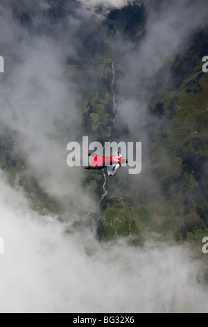 Parachutiste au sein d'une wingsuit spécial est un nuage volant le long d'avance sur beau terrain scape paysage. Le Birdman va avancer rapidement. Banque D'Images