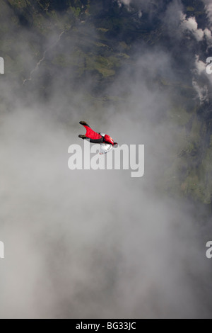 Parachutiste au sein d'une wingsuit spécial est un nuage volant le long d'avance sur beau terrain scape paysage. Le Birdman va avancer rapidement. Banque D'Images