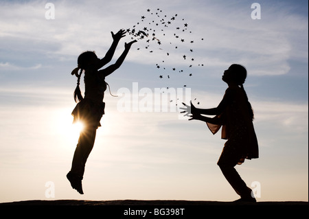 Silhouette de deux jeunes filles indiennes sauter, lancer et attraper des étoiles. L'Inde Banque D'Images