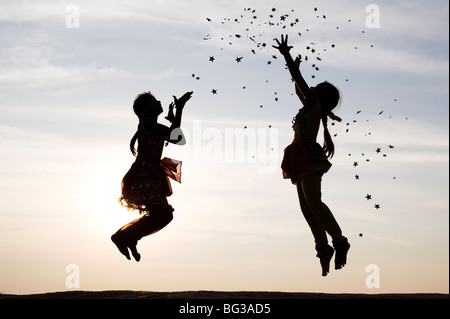 Silhouette de deux jeunes filles indiennes sauter, lancer et attraper des étoiles. L'Inde Banque D'Images