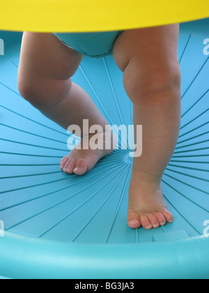 Les jambes et les pieds d'un enfant l'apprentissage de la marche dans un environnement bleu Banque D'Images