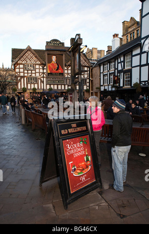 Royaume-uni, Angleterre, Manchester, rue Cateaton, shoppers Noël extérieur potable vieux Inn Wellington Banque D'Images