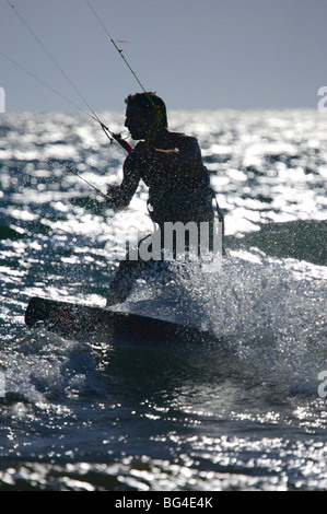 Silhouette d'un kite surfer contre la fin de l'après-midi avec sun spray éclairé et les gouttelettes d'eau. Banque D'Images