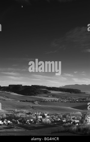 Village de Liptov, Kvacany, Slovaquie, à l'automne coucher du soleil avec la Lune en première moitié sur le ciel sombre, version bw Banque D'Images