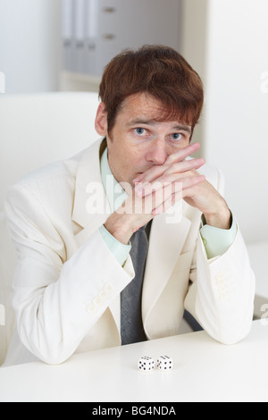 Le jeune homme dans un costume blanc est assis à une table Banque D'Images