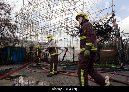 Trois London Fire Brigade les pompiers suivent à la combustion lente reste après une succession de feu dans le sud de Londres. Banque D'Images