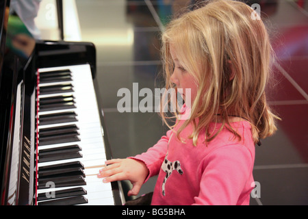 Jeune fille blonde de l'âge des enfants âgés de 3 ans à jouer de la musique sur le clavier de piano Banque D'Images